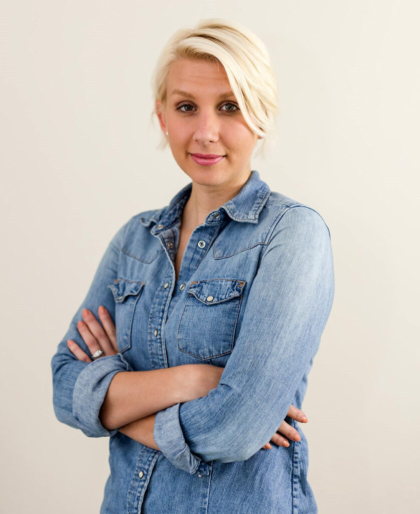 A woman in blue shirt with her arms crossed.