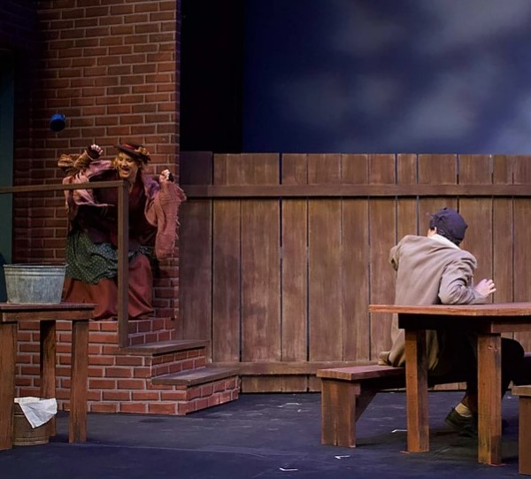 A man sitting at a table in front of a brick wall.