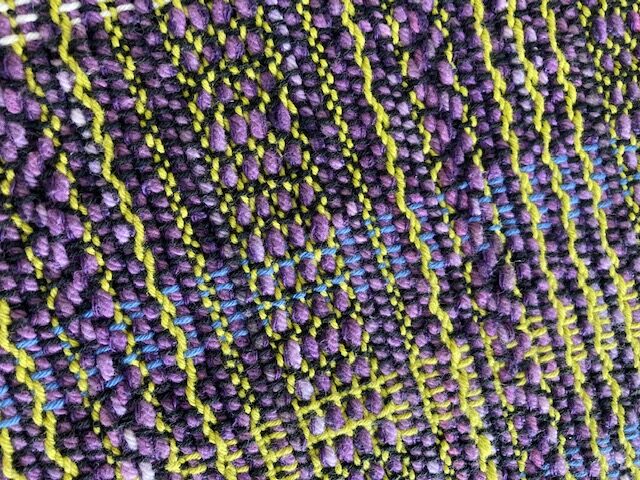 A close up of the fabric with purple and yellow patterns