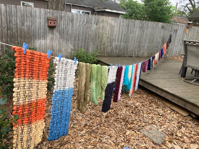 A bunch of yarn hanging on the line outside