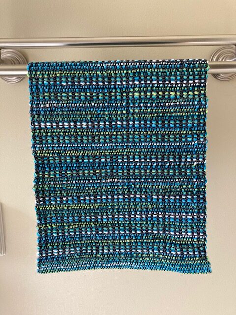 A blue and green knitted blanket hanging on the wall.