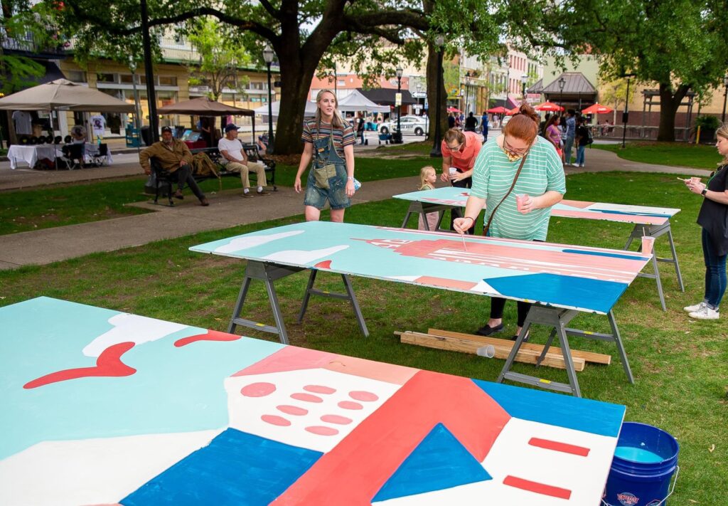 People painting a table in the grass.