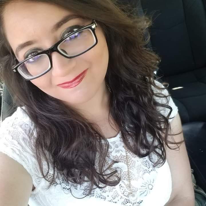 A woman with glasses sitting in the back of a car.