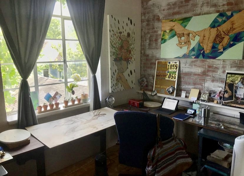 A room with a desk and chair, a window and a painting.