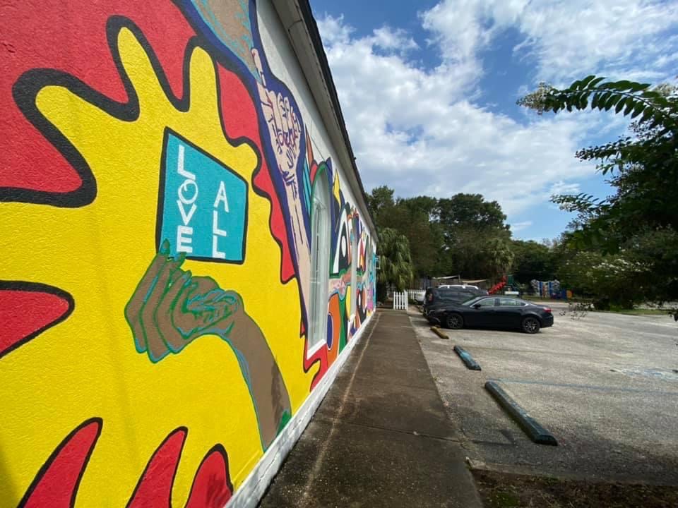 Colorful mural with "Love All" message.