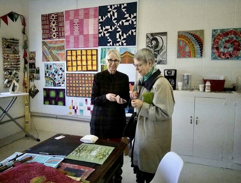 Two women standing in a room with some papers on the table.