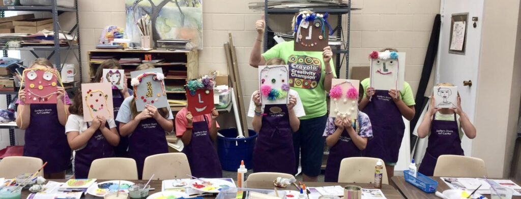 A group of people holding up masks in front of their faces.