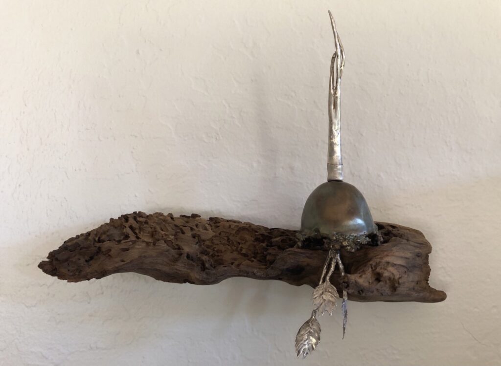 A metal bell hanging on top of a piece of wood.