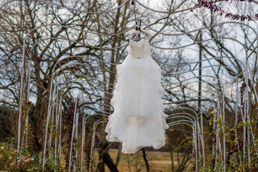 A white dress hanging from metal bars in the middle of a field.