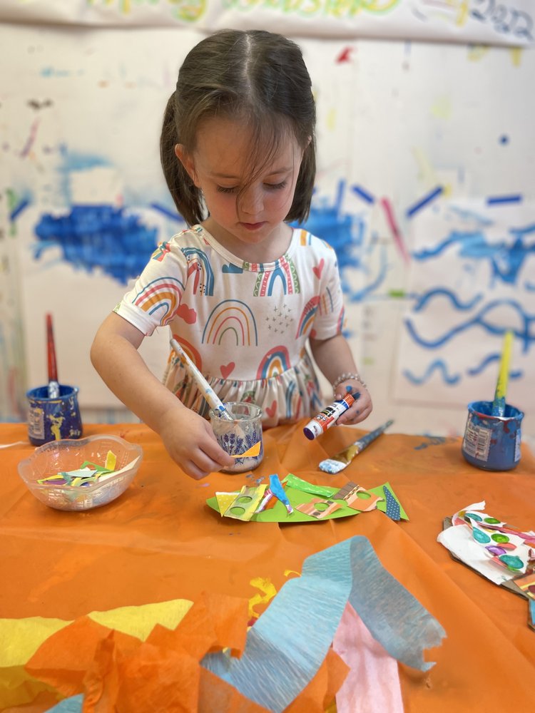 A little girl is making paper crafts at the table.