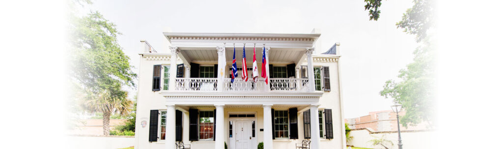 A white house with four flags on the front of it.