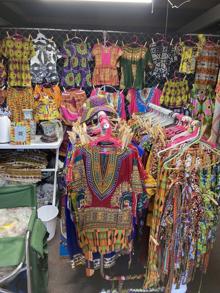 A person in colorful clothing standing next to a display of clothes.