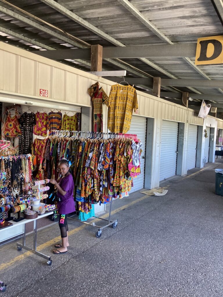 A woman standing in front of a store with many items.